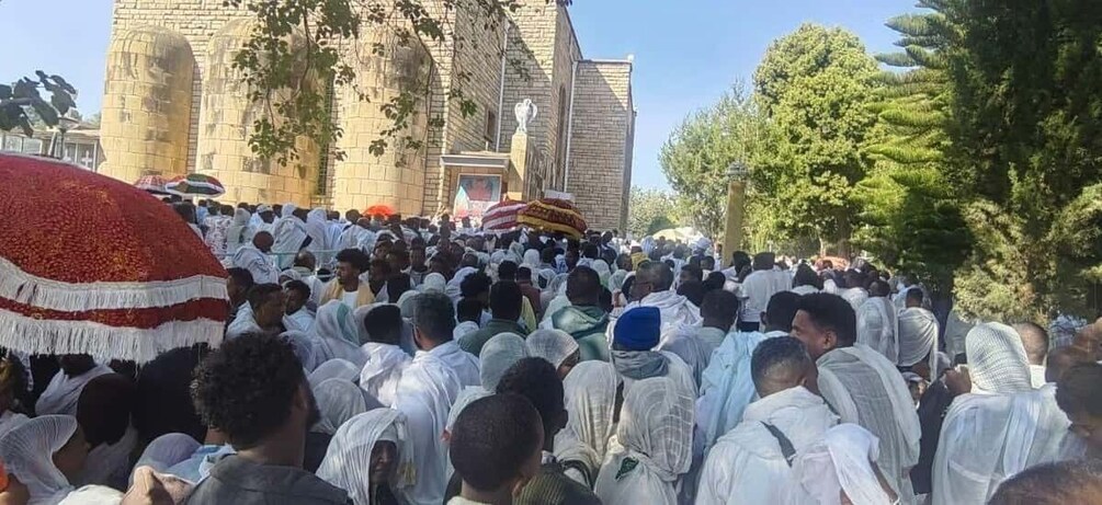 A large crowd gathered in front of a building with a statue. 3