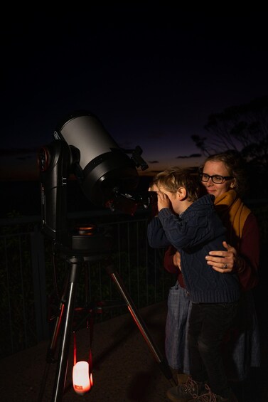 Two people observing through a telescope at night. 3