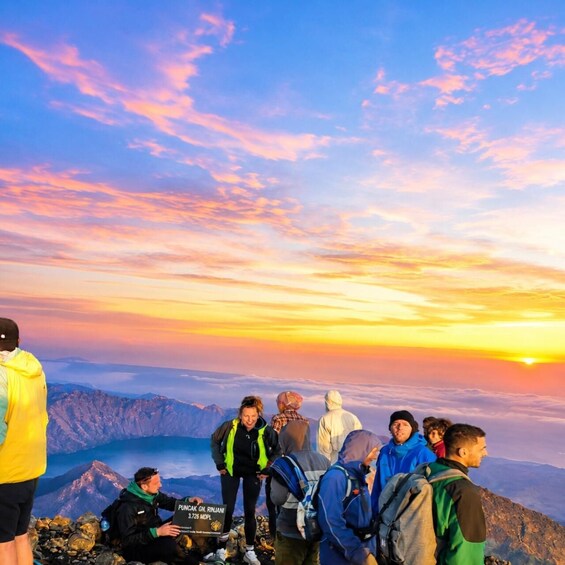 A group of hikers on a mountain with a sunset in the background. 2
