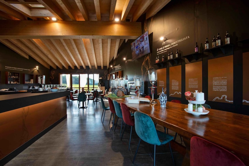 A modern bar with wooden beams, a long counter, and colorful chairs. 2