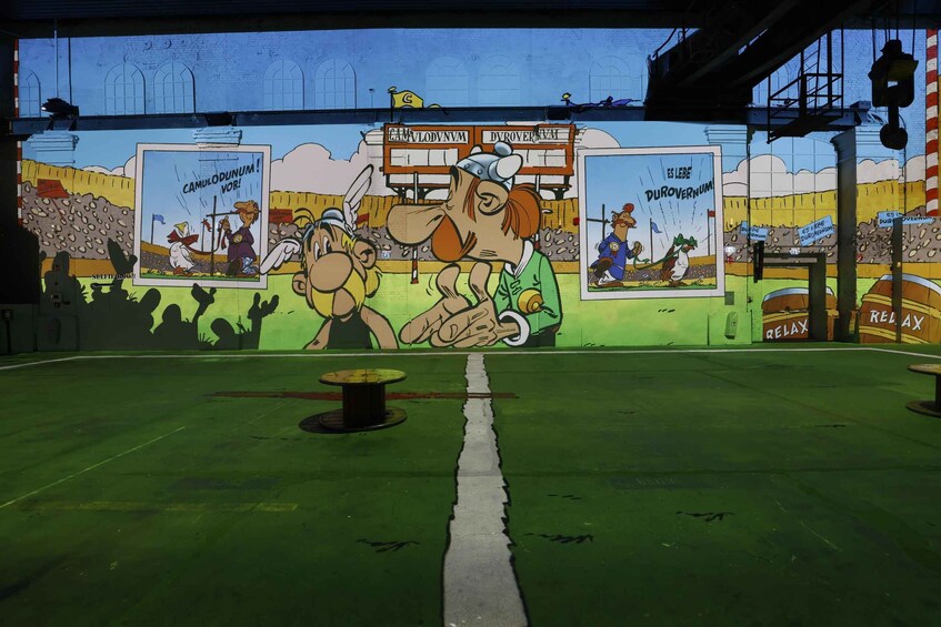 A mural with cartoon characters and text, a green floor, and a table. 3