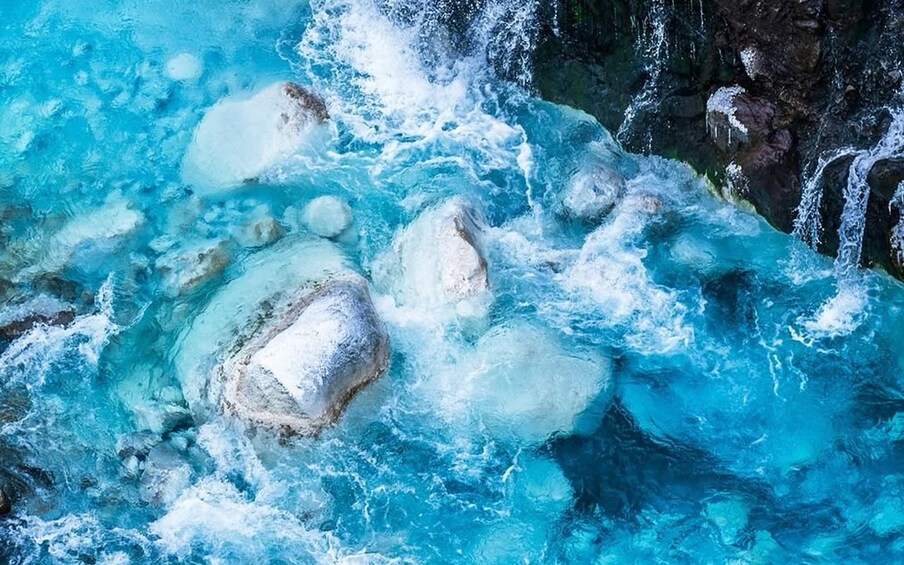 A turbulent river with clear water, ice formations, and rocky terrain. 2