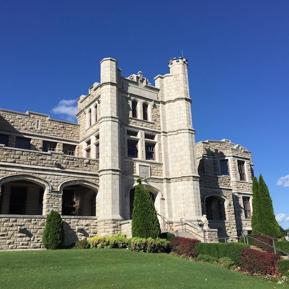 A large stone building with a tower, arched windows, and a well-maintained lawn. 1