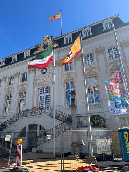A historic building with ornate architecture, multiple flags, and a clock tower. 5