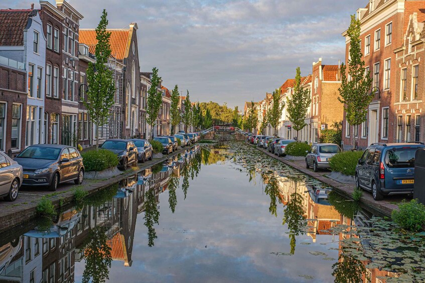 A canal with buildings and parked cars on either side. 3