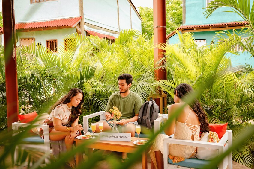 A group of people dining outdoors surrounded by lush greenery and traditional architecture. 4