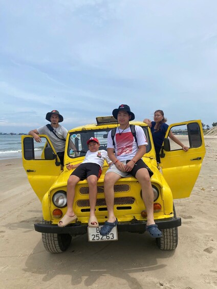 A yellow vehicle with a license plate on a sandy beach. 2