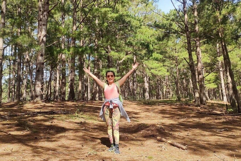 A person standing in a forest with trees and a dirt path. 4