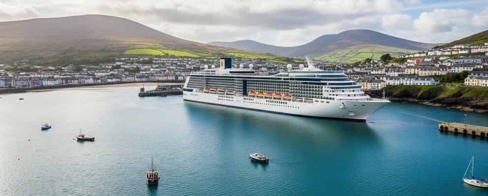 A large cruise ship docked at a port with a mountainous backdrop and a town in the distance. 1