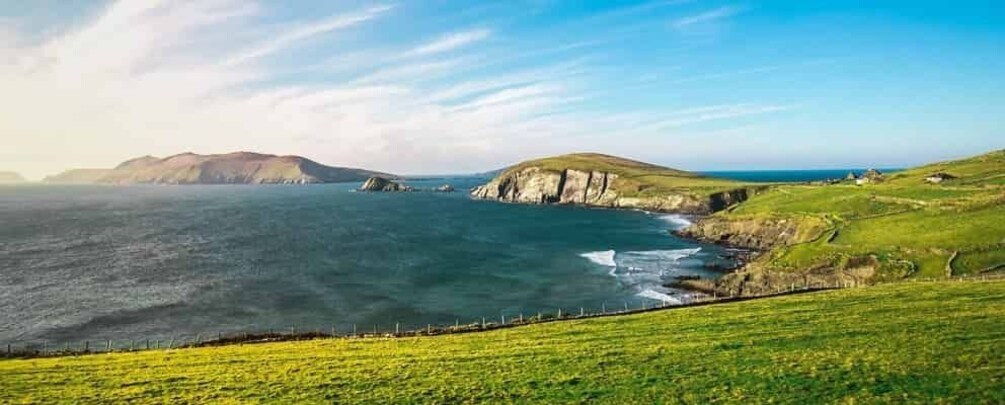 A coastal landscape with grassy hills, cliffs, and the ocean. 3
