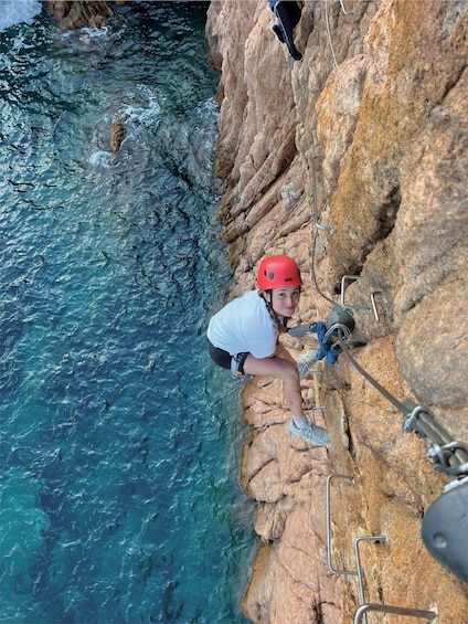 A person rappelling down a rocky cliffside near a body of water. 1