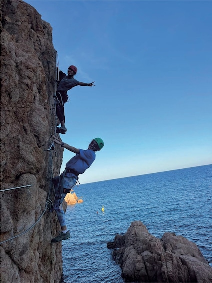 Two people rappelling down a rocky cliff with the ocean in the background. 5