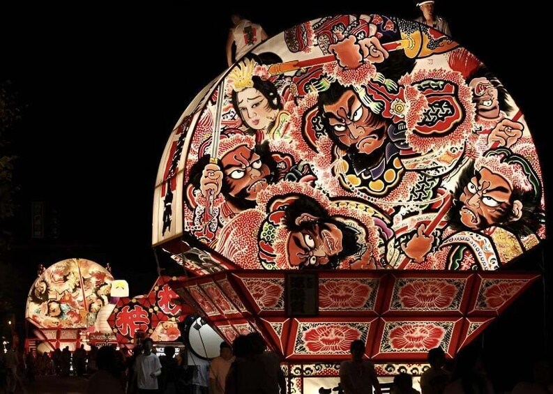 A large illuminated lantern with traditional Japanese artwork. 3