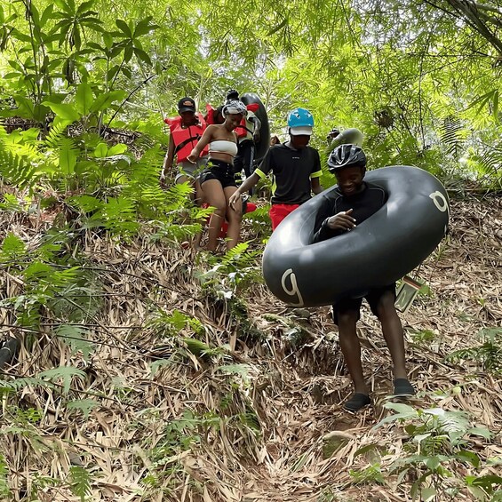 A group of people hiking in a forested area with dense foliage and dry leaves on the ground. 5