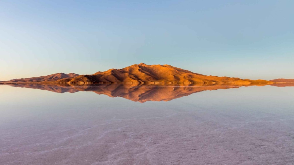 A mountain range reflected in a calm, expansive salt flat. 1