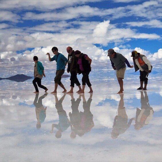 A group of people walking on a reflective surface with mountains in the background. 3