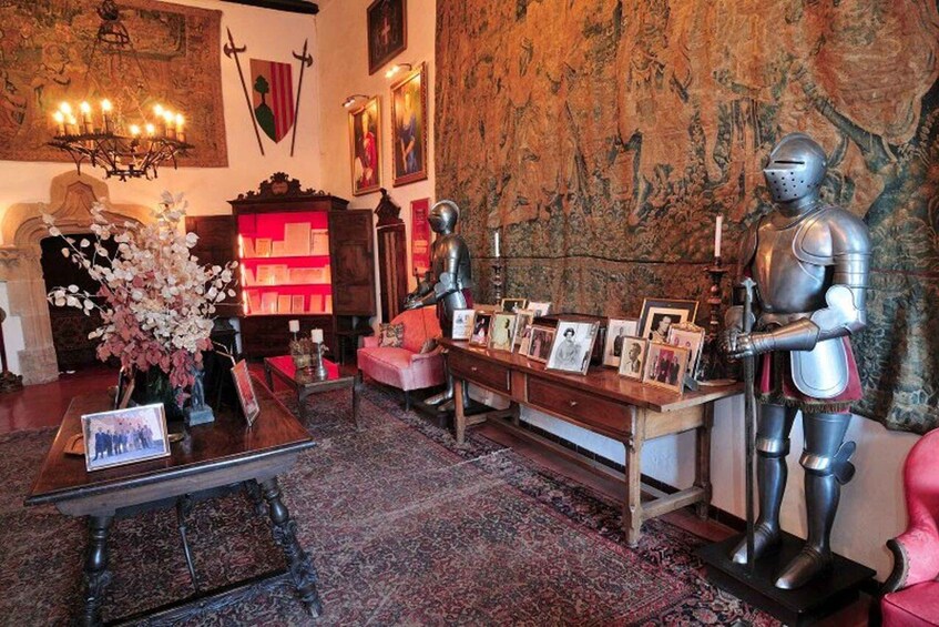 A room with a medieval knight statue, a chandelier, a tapestry, and a bookshelf. 1