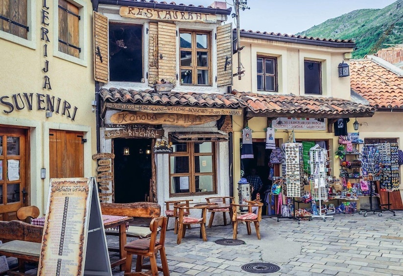 A rustic restaurant named 'Restauranta Suveniri' with outdoor seating and a shop selling souvenirs. 4