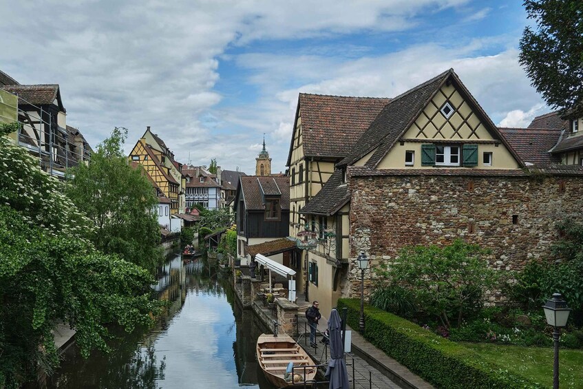 A narrow canal flanked by traditional half-timbered houses with a stone wall on one side. 1