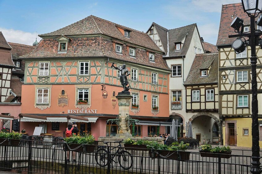 A traditional European town with a restaurant, a statue, and historic buildings. 3