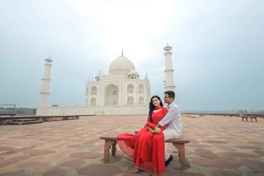 A couple sitting on a bench with the Taj Mahal in the background. 1