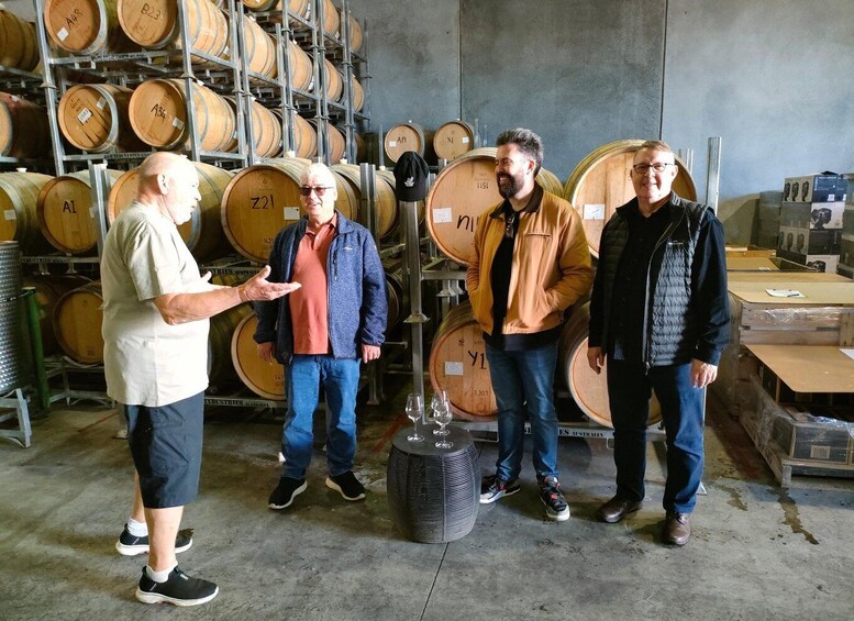 A group of people in a storage room with wooden barrels. 1
