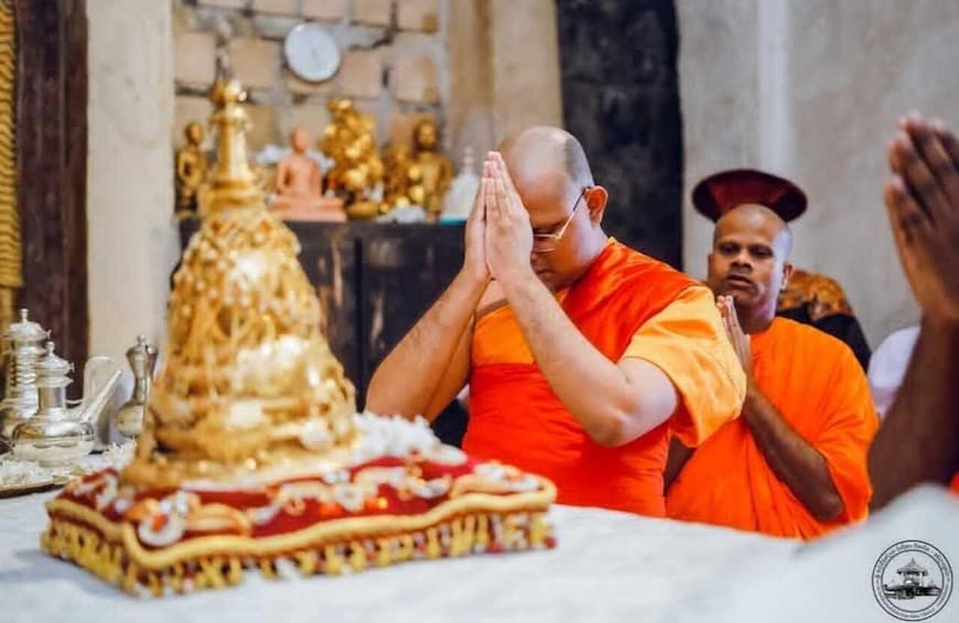 A person in orange robes performing a ritual with hands pressed together. 4