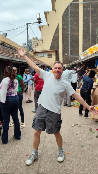 A man dancing in a crowded outdoor market with buildings in the background. 4
