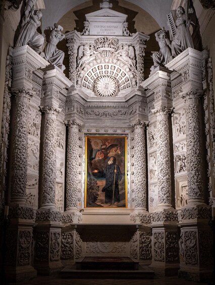 An ornate chapel interior with detailed carvings, a central painting, and statues. 2