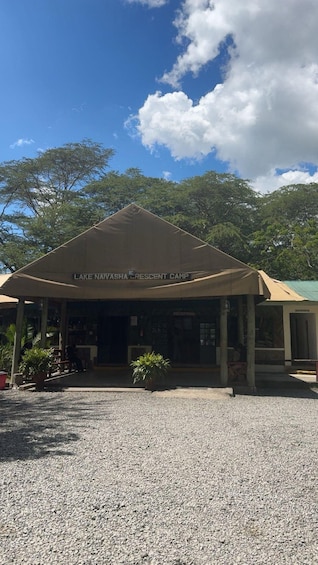 A covered pavilion labeled 'Lake Naivasha Crescent Camp' with a gravel driveway and potted plants. 4
