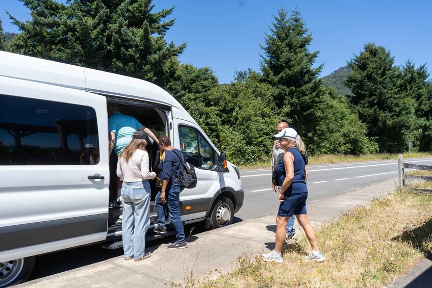 A white van parked by the roadside with people boarding it. 2
