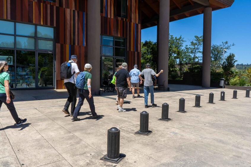 People walking in front of a modern building with large windows and a unique facade. 3