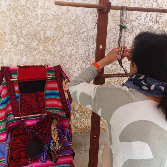 A person weaving on a loom with colorful textiles. 1