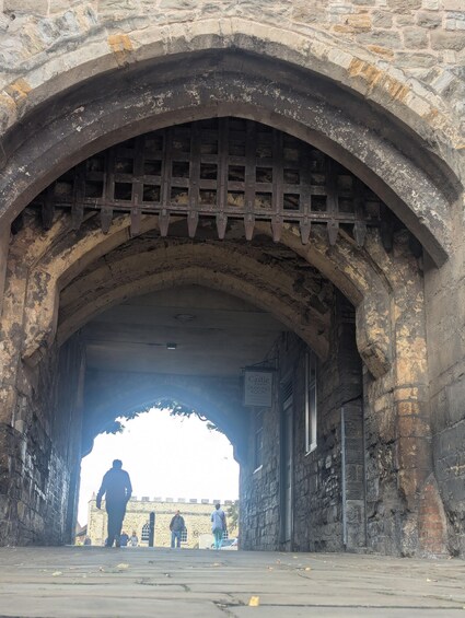 An arched stone bridge with a sign for 'The Castle Drawing Room' visible in the distance. 2