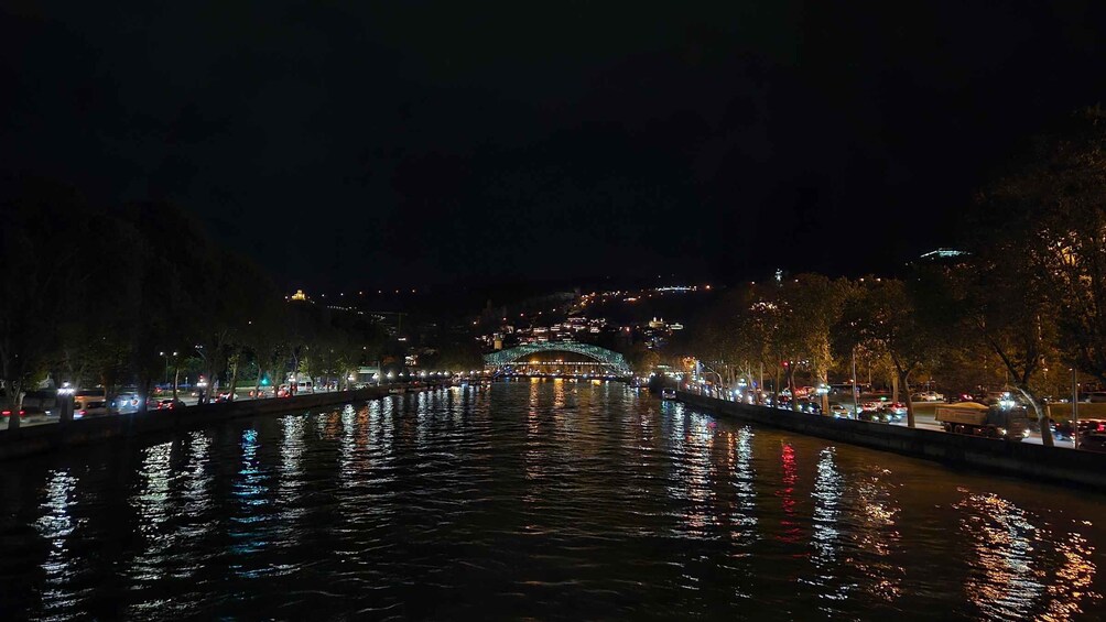 A nighttime river with illuminated buildings and a bridge in the distance. 5