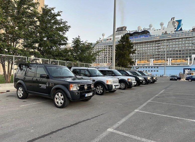 A row of SUVs parked in a lot with a cruise ship in the background. 1