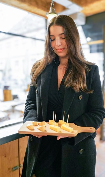 A person holding a wooden tray with several rectangular food items. 1