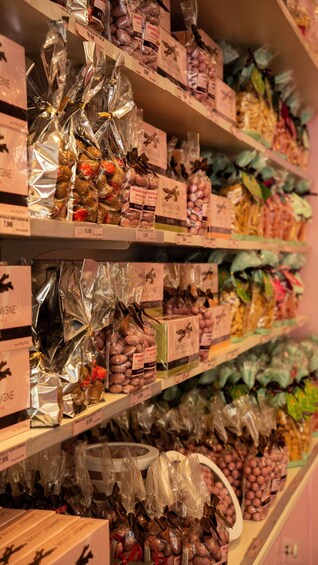 Shelves stocked with various packaged food items, including chocolates and nuts, with price tags. 2