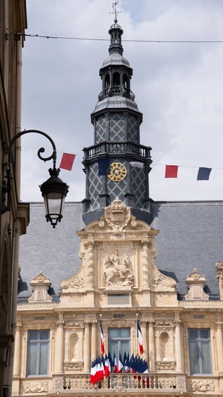 A historic building with a clock tower, ornate sculptures, and flags. 5
