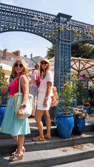Two women standing in front of a blue metal gate with the inscription 'The Garden of Eden.' 3