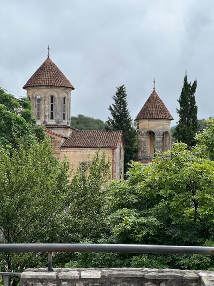A church with two bell towers and a stone building with a red-tiled roof. 2