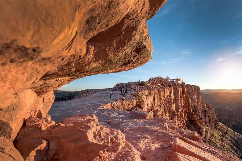 A rock formation with a clear sky and a distant view of a cliff with people. 4