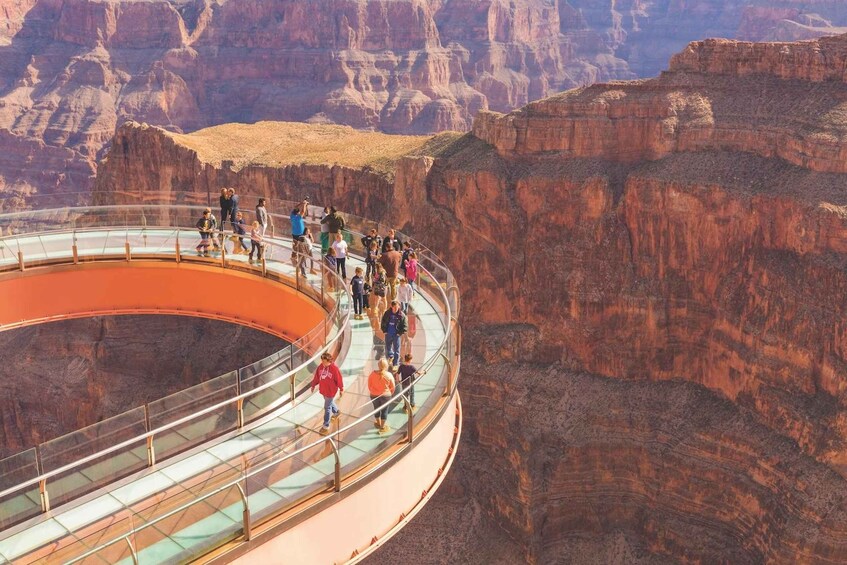 A glass-bottomed walkway with people walking along it, surrounded by canyon walls. 1