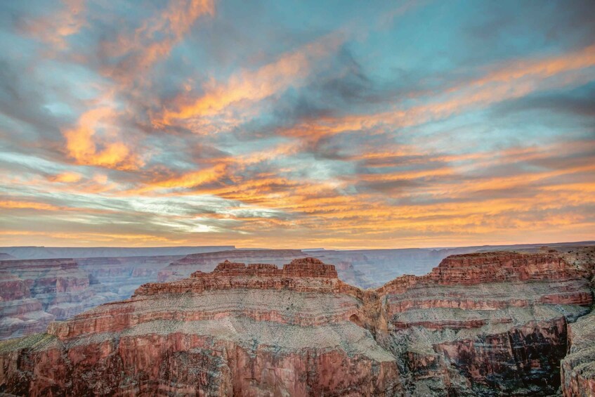 A canyon with layered rock formations and a colorful sunset sky. 2