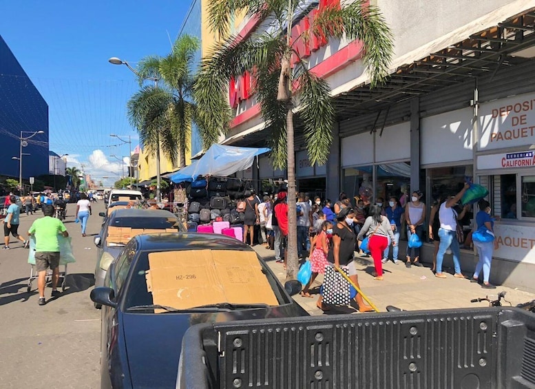 A busy street with people, a truck, and a building with a sign that reads 'DEPOSITO DE PAQUETAS'. 2