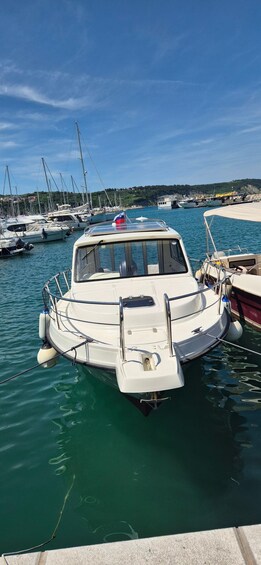 A white boat docked at a marina with other boats in the background and a clear blue sky. 3