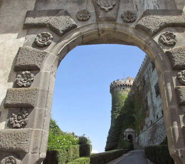 An arched stone gateway with floral carvings leading to a castle. 1