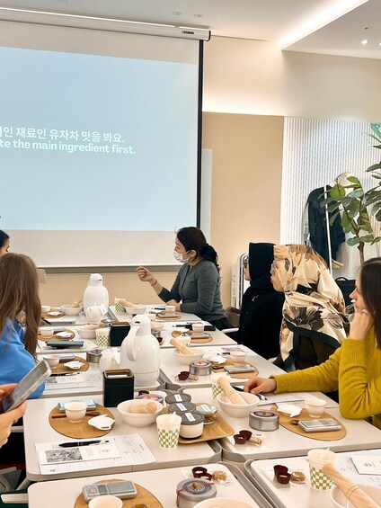 A group of people seated around a table with various bowls and utensils, likely participating in a cooking or baking class. 1