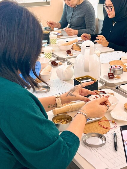 A group of people engaged in a cooking activity, with various kitchen utensils and ingredients on the table. 5