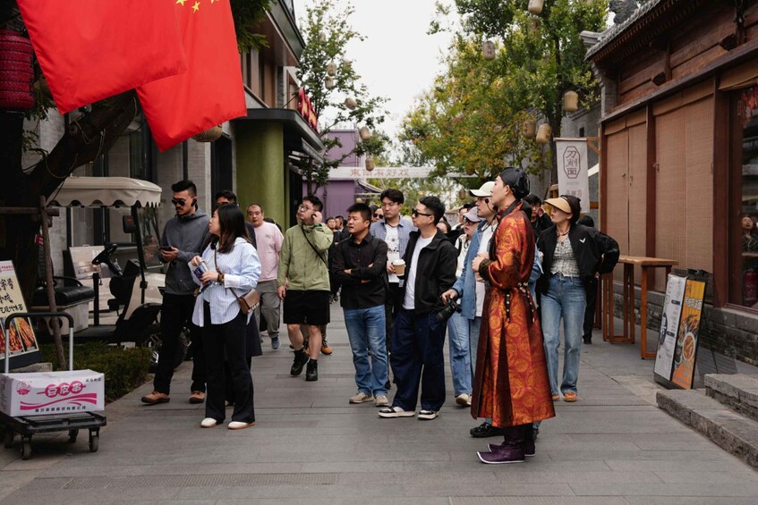 A street scene with people walking, a red flag, and traditional architecture. 2